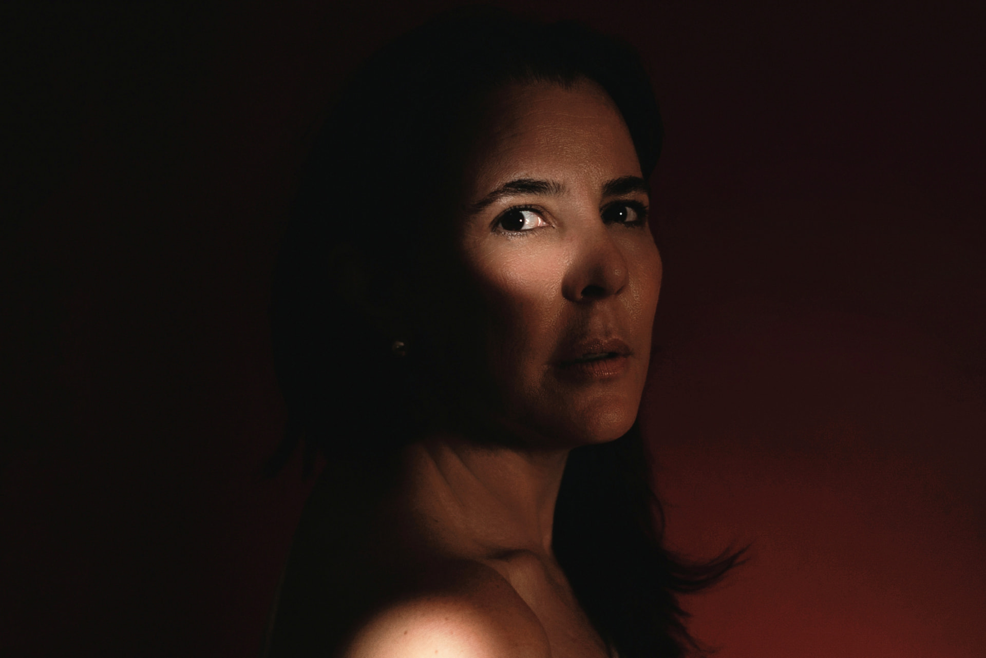 Retrato cercano con luz cálida sobre fondo rojo oscuro