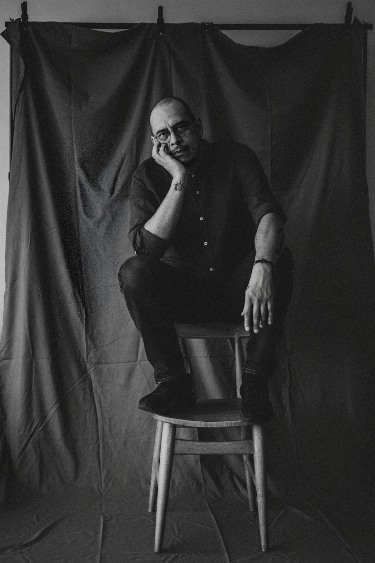 Retrato en blanco y negro de Ricardo sentado frente a una tela oscura